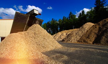 Mavi gökyüzüne karşı ahşap yakıt deposu olan biyo-elektrik santrali