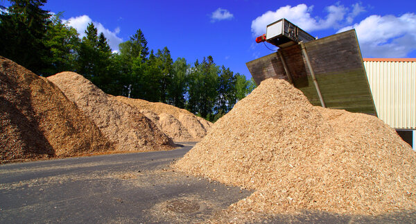 bio power plant with storage of wooden fuel against blue sky