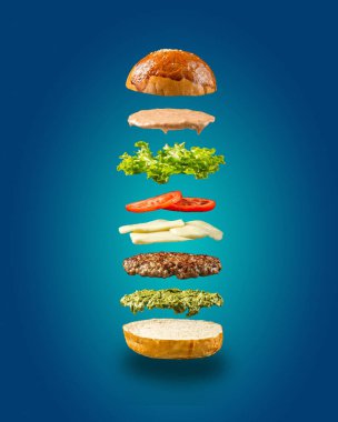 Mavi arka planda yüzen hamburger malzemeleri