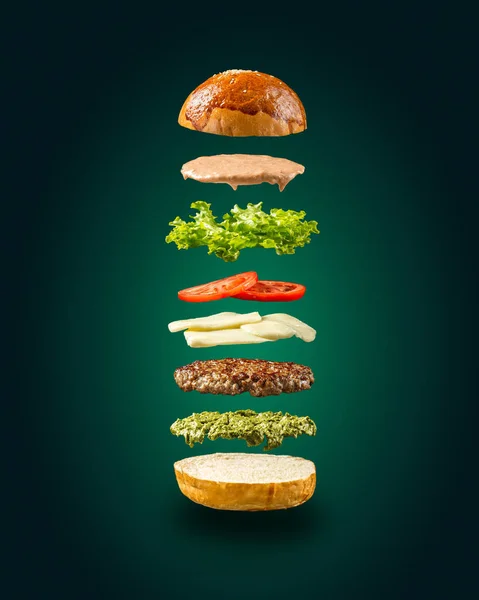 Ingrédients de hamburger flottants sur fond vert — Photo
