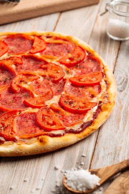 Domatesli jambonlu pizza ve kurutulmuş otlar.