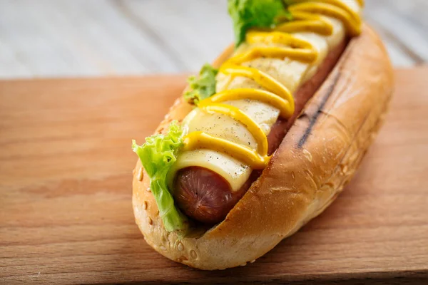 Kaas hotdog met mosterd op het houten bord — Stockfoto