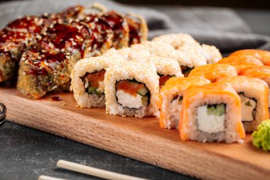 Tahta bir tahtanın üzerinde çeşitli suşi rulolarına yakın çekim.