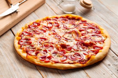 Ahşap kırsal masada sosisli pizza avlıyor.