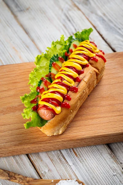 Hot dog with mustard and ketchup on wooden board — Stock Photo, Image