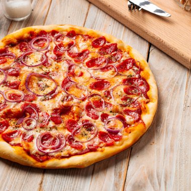 Ahşap kırsal masada sosisli pizza avlıyor.