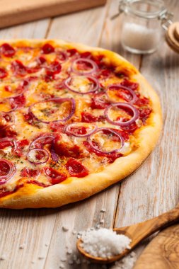 Ahşap kırsal masada sosisli pizza avlıyor.