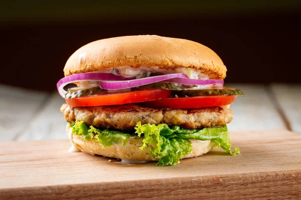 Chickenburger with pickles on the wooden board — Stock Photo, Image