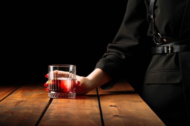 Bir bardak negroni kokteyli tutan adam.