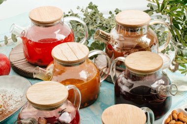 Mavinin üzerinde cam kaplarda çeşitli meyve çayları.