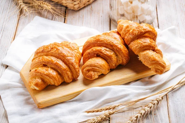 Tři francouzské croissanty na dřevěné desce — Stock fotografie