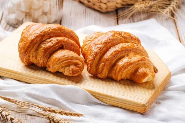 Dva francouzské croissanty na dřevěné řezací desce — Stock fotografie