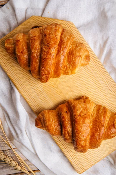 Dva francouzské croissanty na dřevěné řezací desce — Stock fotografie