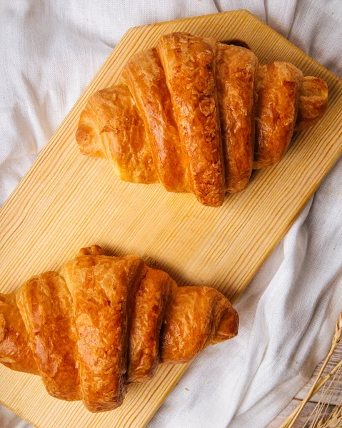 Dva francouzské croissanty na dřevěné řezací desce — Stock fotografie