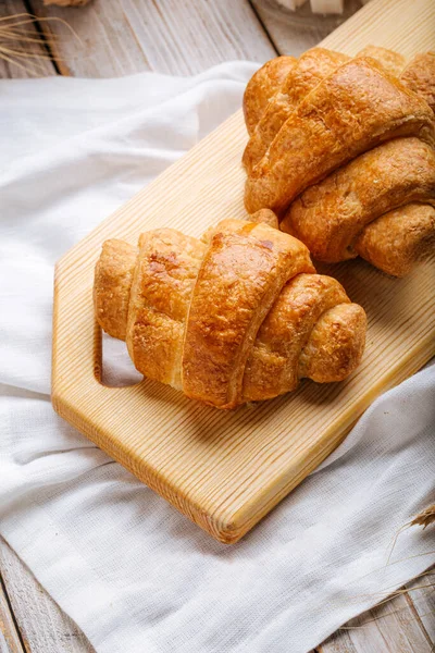 Dva francouzské croissanty na dřevěné řezací desce — Stock fotografie