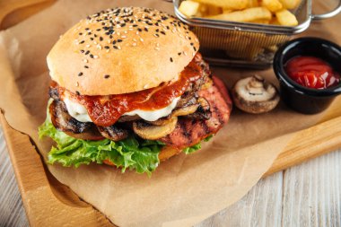 Mantar ve domates soslu burger ve patates kızartması.