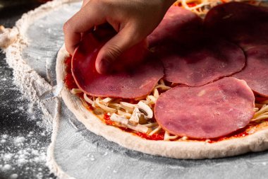 Hamurun üzerine jambon seren bir pizza yapmak