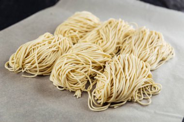 Parşömen kağıdında çiğ yumurtalı erişte yuvaları var.