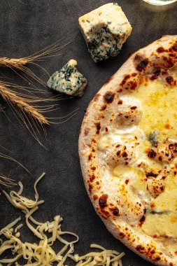 Süslü arka planda dört peynirli pizza.