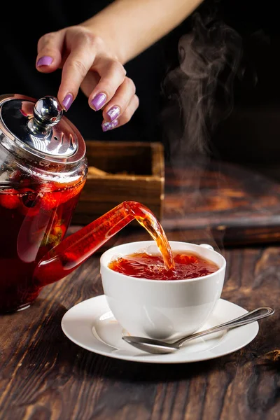 Les mains de femme versant le thé chaud dans une tasse de pot — Photo