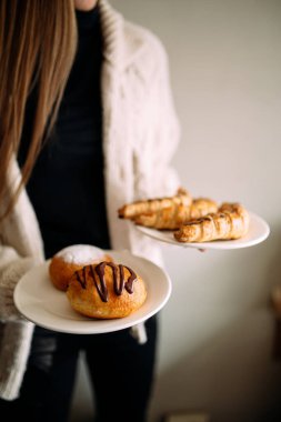 Kadın elinde iki tabak tatlı çörek ve simit tutuyor.