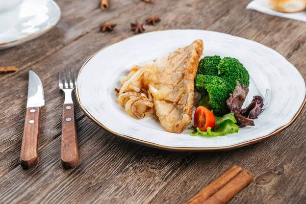 Филе жареной рыбы с овощами на столе — стоковое фото