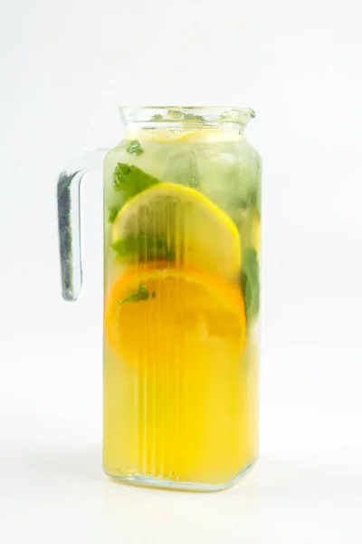 Ізольований скляний глечик жовтого лимонаду з м'ятою — стокове фото
