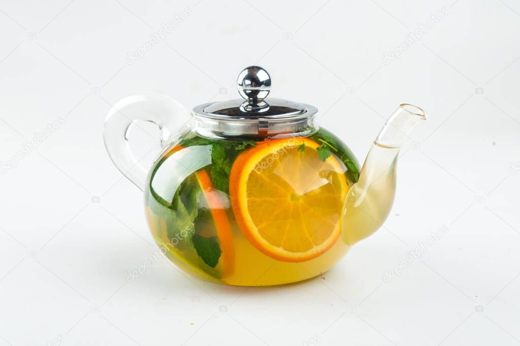 Isolated teapot of green tea with orange and mint