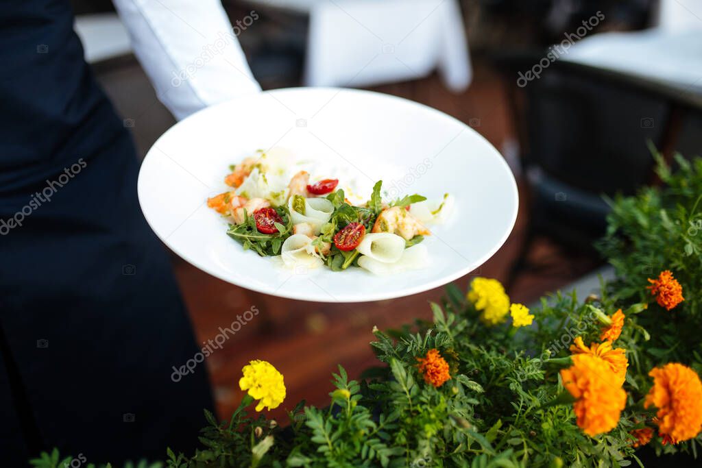Waiter holding plate of gourmet shrimp salad