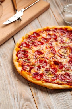 Ahşap kırsal masada sosisli pizza avlıyor.