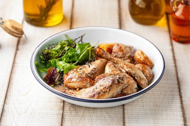 Grilled chicken wings served with fresh mixed greens and roasted potatoes on a rustic white plate