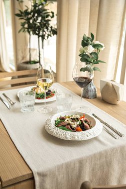 Meyveli sığır eti salatası, kırmızı ve beyaz şarapla servis edilir.