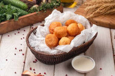 Kırsal bir masada soslu bir sepette servis edilen altın gevrek baursak parçaları.