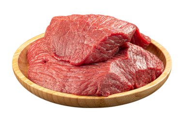 Beyaz arka planda yuvarlak ahşap bir tabakta duran izole edilmiş çiğ et parçaları taze kırmızı etin dokusunu ve rengini gösteriyor.