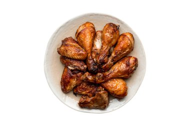 İzole edilmiş kızarmış tavuk budu, beyaz arka planda seramik bir tabağa yerleştirilmiş.