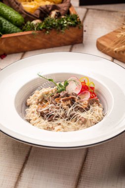 Sotelenmiş mantar, rendelenmiş peynir ve taze sebzelerle servis edilen kremalı risotto.