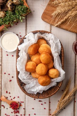 Kırsal bir masada soslu bir sepette servis edilen altın gevrek baursak parçaları.