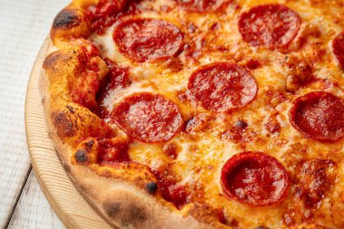 Domates soslu acı biberli pizza ve ahşap bir tahtanın üzerinde eritilmiş peynir.