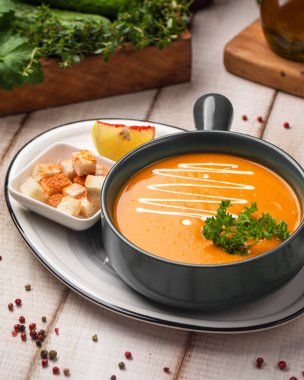 Sıcak kremalı balkabağı çorbası taze bitkilerle servis edilir çıtır çıtır çıtır çıtır ve bir dilim şeftali