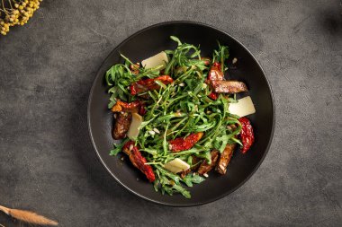 Lezzetli roka salatası. Yumuşak et dilimleri, kurutulmuş domatesler, parmesanlı otlar.