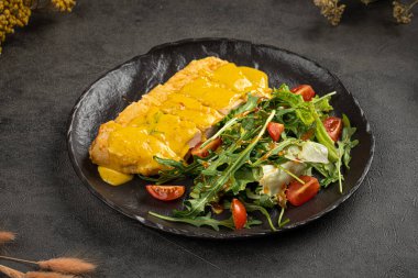 Hardal soslu ızgara tavuk filetosu ve koyu tabakta taze salata.