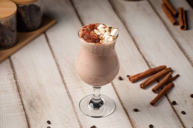 Kakao tozu ve marşmelovla kaplanmış kremalı çikolatalı içecek kırsal ahşap masada servis edilir.