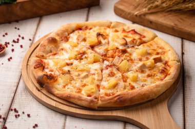 Ananas, peynir ve jambonla kaplı klasik Hawaii pizzası, ahşap bir masada servis edilir.