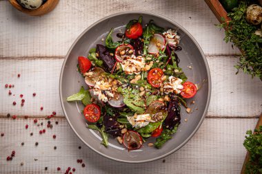 Taze salata, kiraz domatesleri yeşiller ve kırsal masada servis edilen gevrek fındıklar.