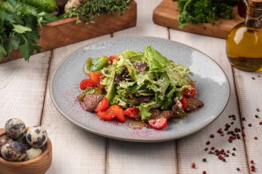 Taze et salatası, yeşil yapraklı, kiraz domatesli ve sade bir masada seramik tabakta servis edilen hafif soslu.