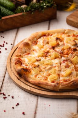 Ananas, peynir ve jambonla kaplı klasik Hawaii pizzası, ahşap bir masada servis edilir.