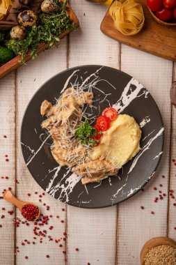 Kremalı sosta pişirilmiş klasik sığır stroganofu pürüzsüz patates püresi ve siyah bir tabakta otlarla servis edilir.