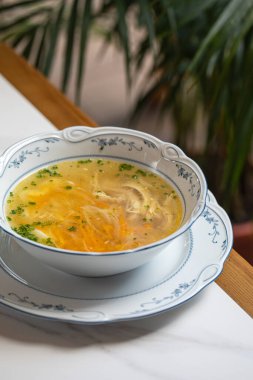 Porselen kasede servis edilen taze havuç ve taze bitkilerle klasik tavuk çorbası.