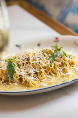 Üzerine rendelenmiş peynir ve taze otlar konmuş kremalı makarna.