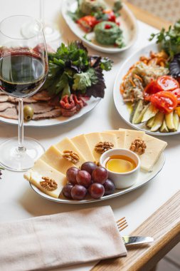 Peynirli, üzümlü, fındıklı, mezeli ve bir bardak şaraplı bir masa.